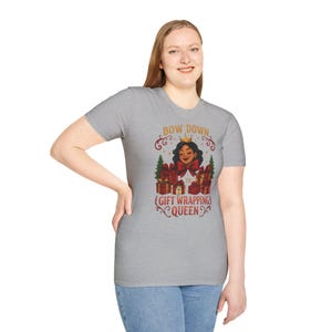 May include: A heather gray t-shirt with the text "BOW DOWN TO (GIFT WRAPPING) QUEEN" in red and gold. The graphic features a woman with a crown and wrapped gifts.