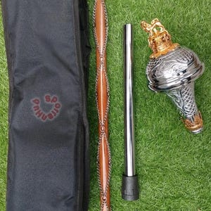 May include: A brown wooden mace with silver chain accents, a silver and gold decorative head, a silver pole, and a black carrying case. The carrying case has the text "PAHU ORRS" in red.