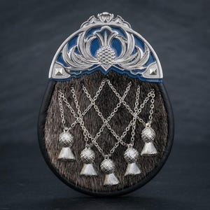 Puede incluir: Un sporran con cuerpo de piel marrón oscuro y borde de cuero negro. La solapa superior está adornada con una placa de metal plateado con incrustaciones de esmalte azul y un motivo de cardo. Tres cadenas plateadas cuelgan con cinco borlas.