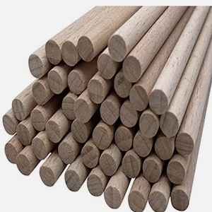 Puede incluir: Un montón de clavijas de madera lisas, de color marrón claro, todas del mismo tamaño, con extremos redondeados.