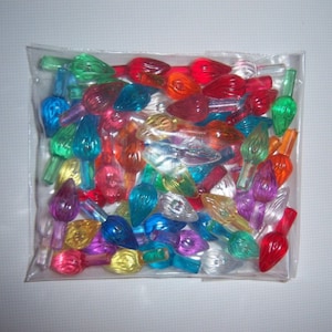 May include: A plastic bag containing a selection of colourful Christmas light bulbs. The bulbs are in various shapes and sizes, all clear with a frosted finish. The bulbs come in a range of colours, including red, green, blue, yellow, orange, and purple.