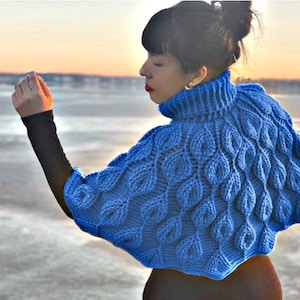 May include: A blue knitted turtleneck sweater with a leaf pattern. The sweater has a high neck and a loose fit.