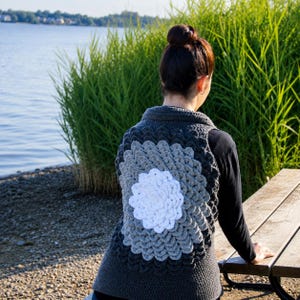 May include: A sleeveless crochet vest featuring a circular mandala-style pattern on the back. The design transitions from a solid white center to light gray, then medium gray, and finally dark charcoal gray, with a solid dark gray base.