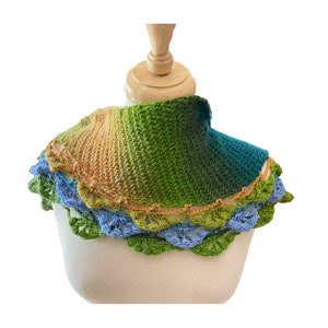 May include: A crocheted cowl with a gradient of orange, yellow, green, and blue colors. The cowl has a crocheted border with a scalloped edge.