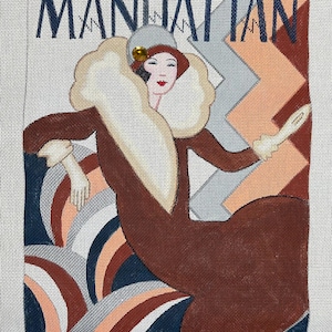 May include: Needlepoint canvas featuring a stylized illustration of a woman in a fur-trimmed coat. The word "MANHATTAN" is at the top in navy blue. The artwork uses a palette of brown, cream, navy, and peach tones, evoking a vintage aesthetic.