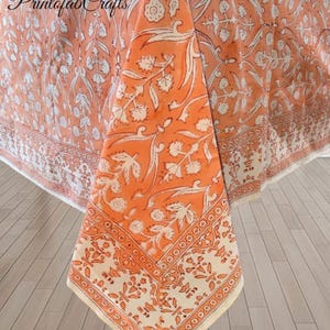 Puede incluir: Mantel floral naranja y blanco con un borde detallado. El mantel presenta un patrón repetido de hojas y flores. El texto "Printofab Crafts" es visible en la esquina superior izquierda. Adecuado para la decoración de comedores y cocinas.