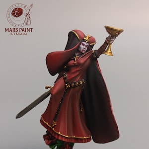 Peut inclure: Figurine miniature d'une femme en robe et cape rouges, tenant un calice doré. Elle a une épée à ses côtés et se tient sur une base carrée. La figurine porte une couronne et un collier en croix.