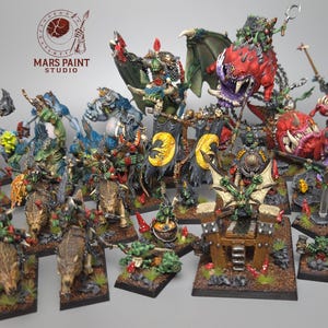 May include: A collection of hand-painted fantasy miniatures, including orcs, goblins, and other creatures. The figures are on individual bases and feature detailed paintwork with various colors. The Mars Paint Studio logo is visible in the upper left.
