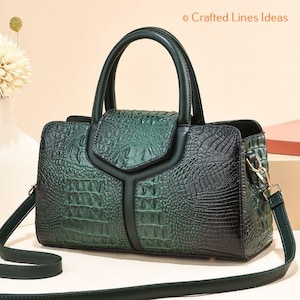 May include: A green and black faux crocodile-textured handbag with a top handle and a detachable shoulder strap. The bag features a flap closure and gold-colored hardware. The text "Crafted Lines Ideas" is visible.