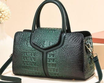 May include: A green and black faux crocodile-textured handbag with a top handle and a detachable shoulder strap. The bag features a flap closure and gold-colored hardware. The text "Crafted Lines Ideas" is visible.