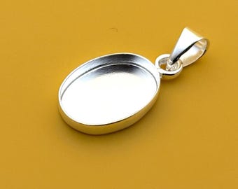May include: A silver-colored oval pendant with a loop for a chain. The pendant has a recessed area for setting a stone or other decorative element. The background is a solid mustard yellow.