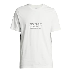 以下が含まれることがあります： 黒い文字で「DEADLINE Est. 18:01 AFTER HOURS RUN CLUB」と書かれた白いTシャツ。Tシャツはクルーネックで半袖です。生地は柔らかく、軽量な素材のようです。