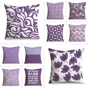 May include: Selection of decorative cushions in shades of purple and white, showcasing diverse patterns. Designs include floral, geometric, and text. One cushion features the text: "TOSS YOUR HAIR IN A BUN DRINK SOME COFFEE PUT ON SOME GANGSTA RAP AND HANDLE IT."