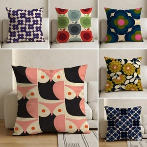 Può includere: Una collezione di cuscini decorativi quadrati con vari motivi in stile retrò. I disegni includono motivi floreali, geometrici e astratti nei colori blu navy, rosa, verde e giallo. I cuscini sono esposti su un divano bianco.