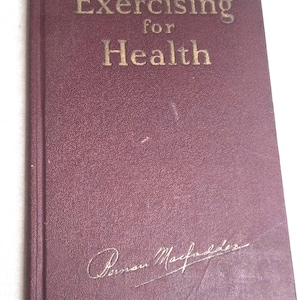May include: A maroon-colored book titled "Exercising for Health" in gold lettering. The book has a textured cover and a signature in gold script at the bottom. The book appears to be vintage.