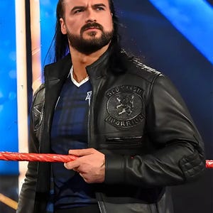 May include: A black leather jacket with a "Scottish Warrior" patch and a blue plaid shirt. The jacket has a quilted design on the shoulders and a metal tag with the numbers "3-2-1". The person is holding a red rope.