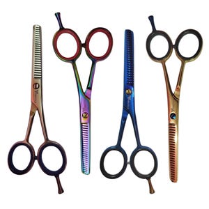 May include: Four pairs of professional hair thinning shears with finger rests and finger rings. The scissors feature varied metallic finishes including silver, iridescent rainbow, deep blue, and gold. Each blade has serrated teeth for thinning.