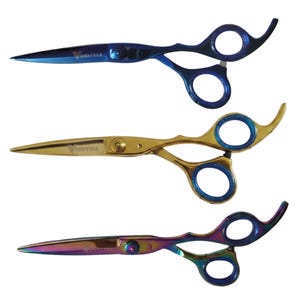 May include: Three pairs of professional hair cutting scissors with finger rests. The top pair is metallic blue, the middle pair is gold with blue accents, and the bottom pair has a multi-colored iridescent finish. Each blade is engraved with the word VERSTYLE.