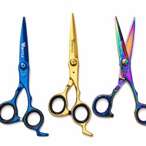 May include: Three pairs of professional scissors with finger rings and finger rests. One pair is metallic blue, one is gold, and one features a multi-colored iridescent finish. Each blade is engraved with the text VERSTYLE near the pivot screw.
