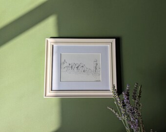 May include: A framed black and white sketch of a landscape scene. The artwork is in a white frame with a light blue mat, hanging on a green wall. A sprig of lavender is in the lower right corner.