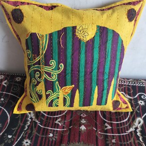 May include: Yellow decorative pillow with a colorful elephant design. The elephant is purple and green with yellow accents. The pillow has a yellow border with brown circular accents and a floral design.