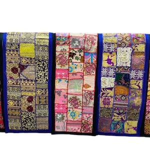 May include: A display of vibrant patchwork textile panels. Each panel is composed of various patterned fabric squares in red, blue, pink, yellow, and gold. The panels are framed with blue and black fabric.