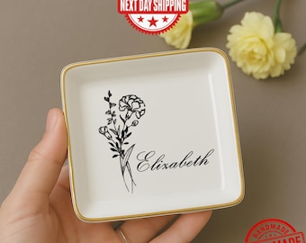May include: A square, white ceramic trinket dish with a gold rim. The dish features a black floral illustration and the name "Elizabeth" in script. The words "Next Day Shipping" and "Handmade" are stamped on the image.