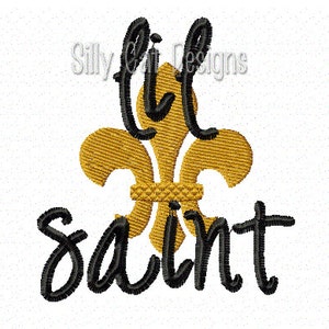 May include: A black and gold embroidery design featuring a fleur-de-lis and the text "lil saint".