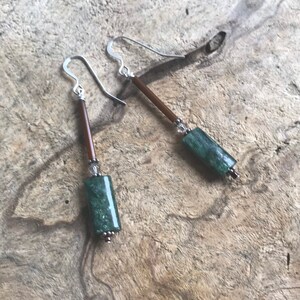 May include: A pair of silver earrings with green stone beads and brown beads.