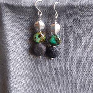 May include: Silver dangle earrings with three beads each. The top bead is silver, the middle bead is turquoise, and the bottom bead is black.