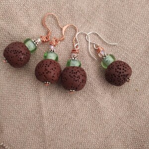 May include: Three pairs of earrings with brown lava rock beads and green glass beads. The earrings have copper and silver wire accents.