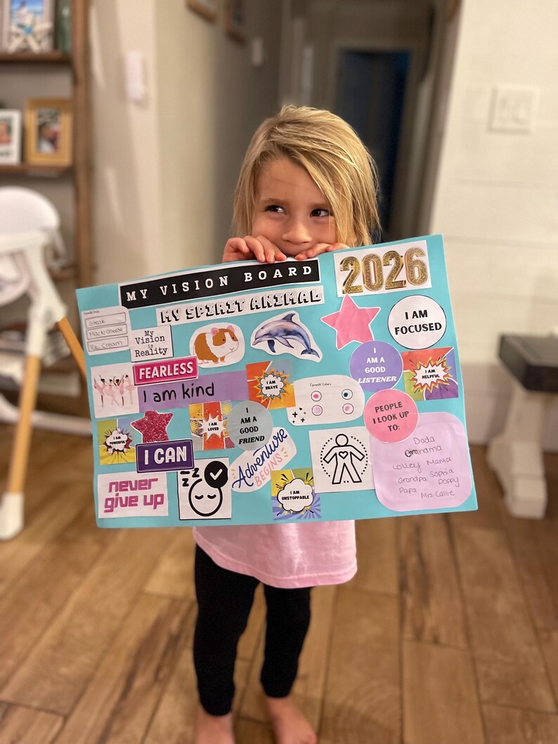 Puede incluir: Un tablero de visi&oacute;n con el texto "MY VISION BOARD" y "2026". El tablero presenta varias im&aacute;genes y frases, incluyendo un conejillo de indias, un delf&iacute;n y las palabras "FEARLESS" y "I CAN". El tablero es sostenido por una persona.