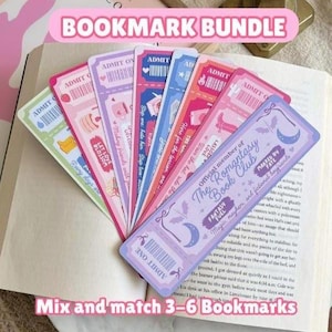 May include: A collection of colourful bookmarks with ticket-style designs. The bookmarks feature phrases like "ADMIT ONE" and "The Romantasy Book Club." The image also includes the text "BOOKMARK BUNDLE" and "Mix and match 3-6 Bookmarks."