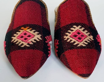 May include: A pair of red and black woven slippers with a geometric pattern. The slippers have a pointed toe and a flat sole.