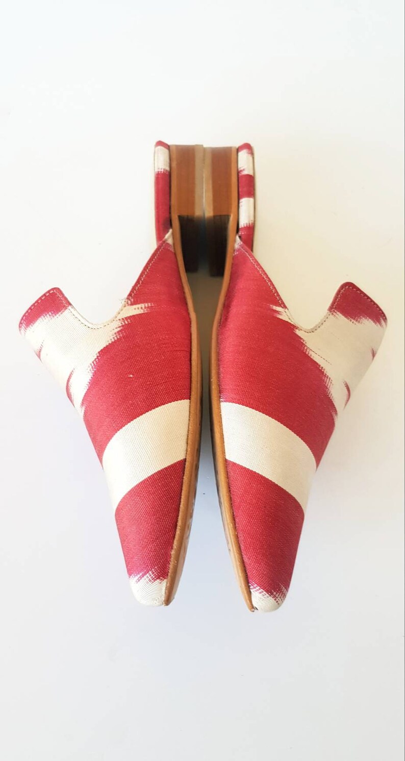 May include: A pair of red and white patterned fabric mules with wooden heels.