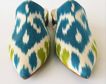 May include: A pair of pointed-toe mules with a white base and a blue and green ikat pattern.