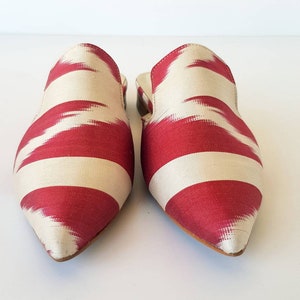 May include: A pair of pointed-toe, red and white striped fabric mules. The fabric has a subtle ikat pattern.