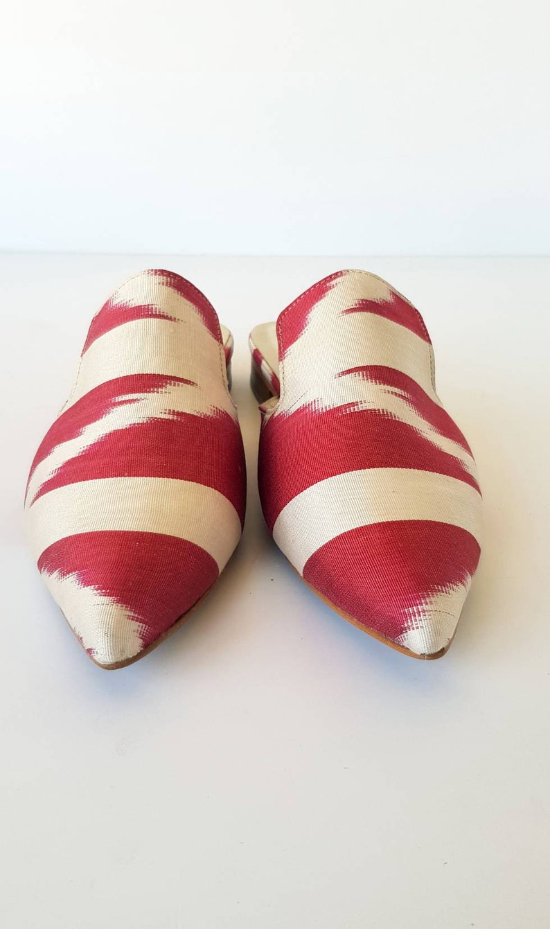 May include: A pair of pointed-toe, red and white striped fabric mules. The fabric has a subtle ikat pattern.