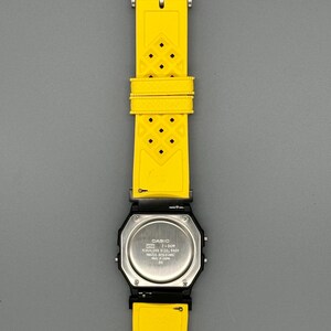 Pode incluir: Um rel&oacute;gio digital Casio preto com uma pulseira de borracha amarela brilhante. O rel&oacute;gio tem uma parte traseira de a&ccedil;o inoxid&aacute;vel e uma fivela prateada. A pulseira amarela tem um padr&atilde;o de diamante.