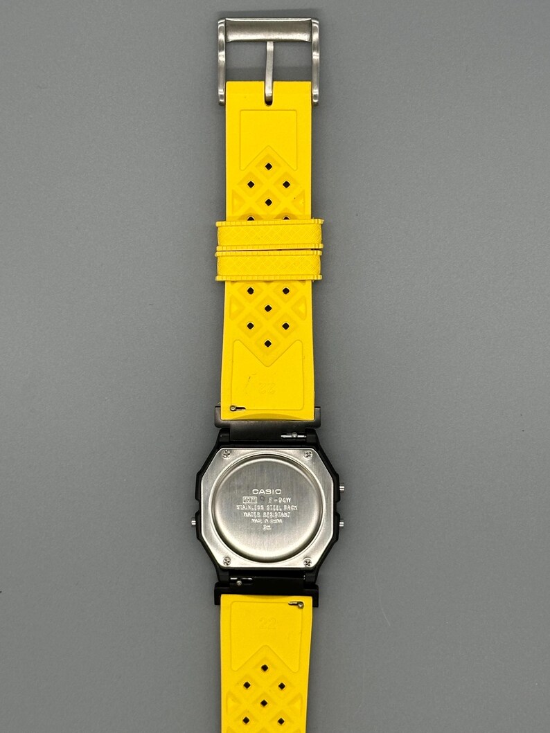 Pode incluir: Um rel&oacute;gio digital Casio preto com uma pulseira de borracha amarela brilhante. O rel&oacute;gio tem uma parte traseira de a&ccedil;o inoxid&aacute;vel e uma fivela prateada. A pulseira amarela tem um padr&atilde;o de diamante.