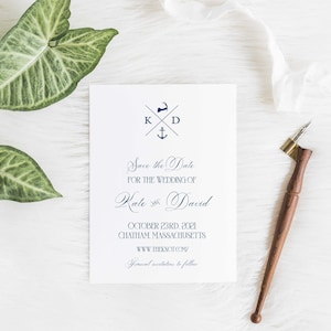 May include: A white save the date card with a navy blue nautical themed design. The card features a monogram with the initials K and D, a nautical anchor, and a stylized image of Cape Cod. The text reads "Save the Date for the Wedding of Kate & David, October 23rd, 2021, Chatham, Massachusetts, www.theknot.com/ Formal invitations to follow."