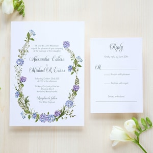 May include: Wedding invitation with a floral wreath design in shades of blue and green. The invitation features the names Alexandra Colleen and Michael R Evans, the wedding date, and the location of the ceremony and reception. The RSVP card includes a space for guests to indicate their attendance and dietary restrictions.