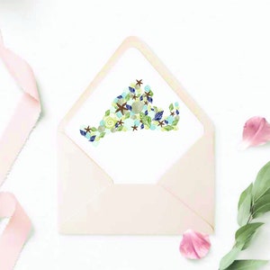 May include: A white envelope with a pink lining. The envelope has a white card inside with a design of a state outline made of seashells, starfish, and other beach-themed elements.