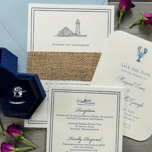 May include: Wedding invitation suite featuring a lighthouse illustration, a lobster save-the-date card, and a reception card. Includes a blue velvet ring box with a diamond ring. The suite is accented with a burlap ribbon.