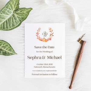May include: Save the date card with a watercolor illustration of a wreath with pumpkins and flowers. The wreath has the initials "S & M" in the center. The text reads "Save the Date for the Wedding of Sephra & Michael, October 23rd, 2021, Falmouth, Massachusetts, www.theknot.com/sephraandmike, Formal invitation to follow."