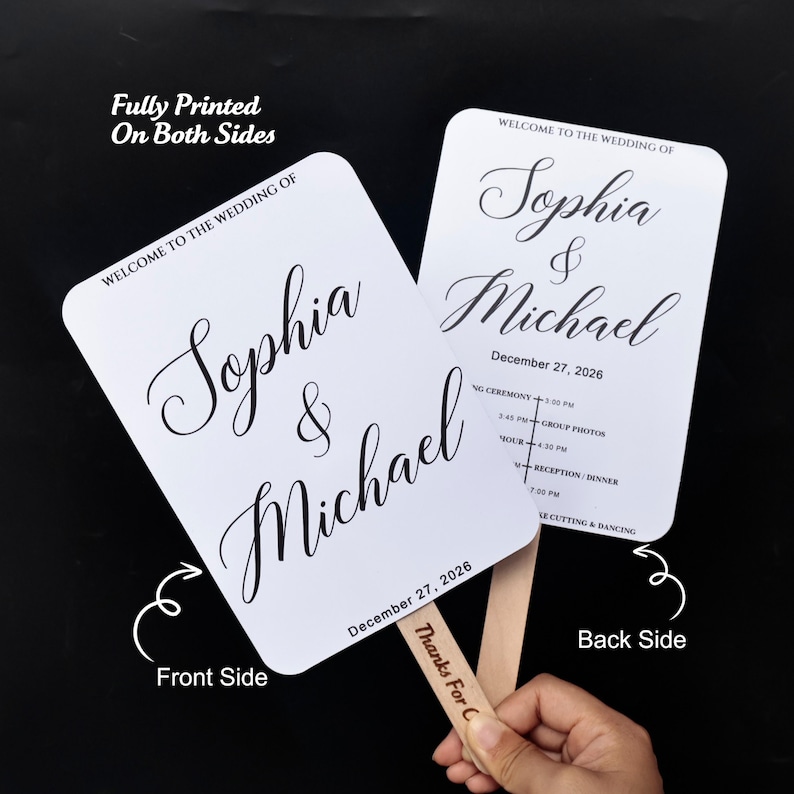 May include: Two white rectangular wedding fans with rounded corners and wooden handles. The front features the text "WELCOME TO THE WEDDING OF Sophia & Michael" and "December 27, 2026". The back includes a wedding schedule and the text "Thanks For C".