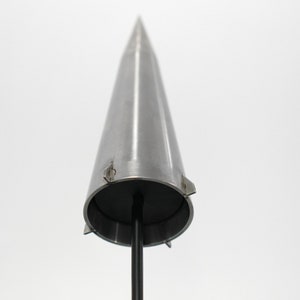 May include: A silver metal cone with a black base and a pointed tip. The cone has a series of small metal tabs around the base.