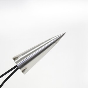 May include: A silver metal cone with a pointed tip and two black wires attached to the base.