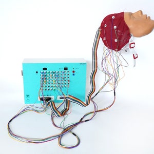 Puede incluir: Una caja azul con una cuadrícula de cables y una cabeza roja con cables conectados a ella. La caja tiene el texto "30 channel". La cabeza es un modelo de cabeza humana.