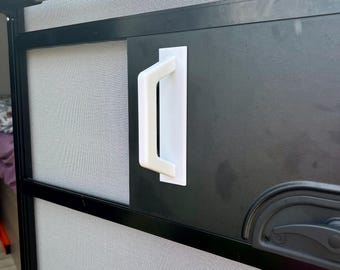 May include: A black screen door with a white handle. The door has a silver bar at the top and a gray mesh screen. The handle is rectangular and mounted on the door's surface.